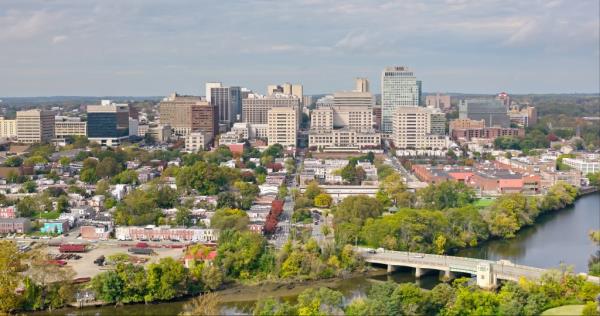 Aerial view of Christina River flowing past downtown Wilmington in Delaware on an overcast fall day, featuring a cityscape with trees and a bridge